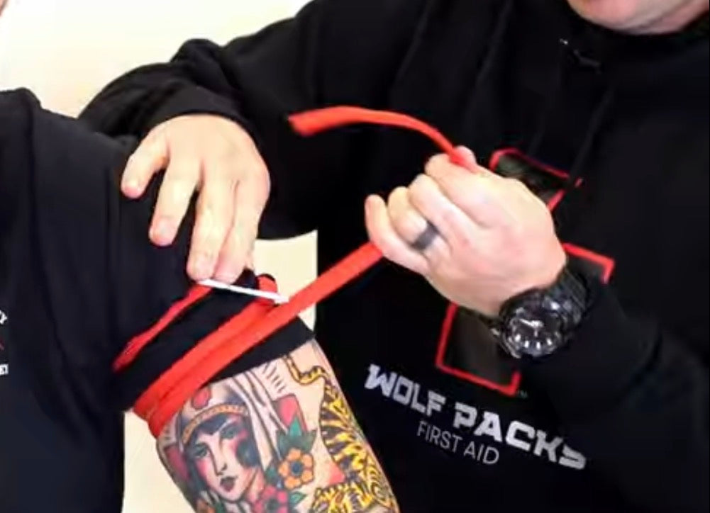 A person applying a tourniquet from a Wolf Packs First Aid pack